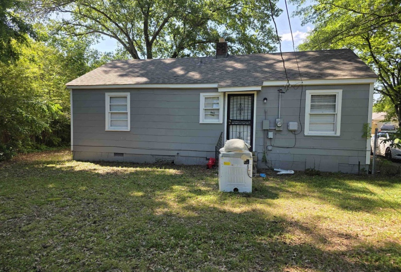 Rear exterior featuring light gray siding, white window trim, and a shingle roof