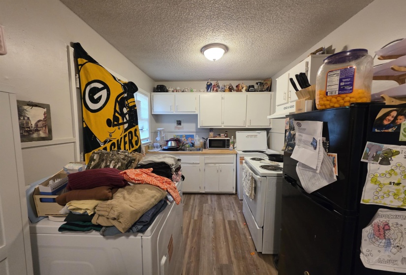 Kitchen area featuring wood-finish flooring, white cabinetry, and white appliances