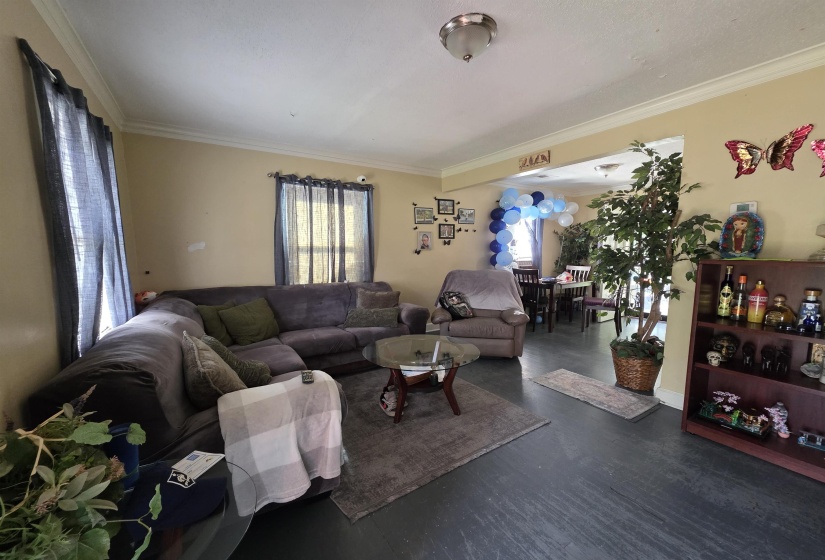 Living area featuring dark flooring, neutral wall paint, and crown molding