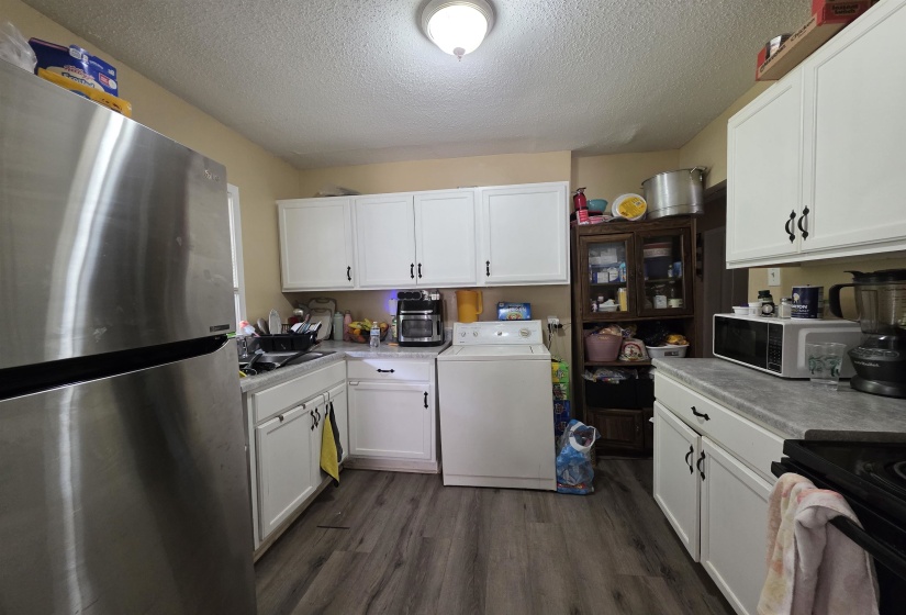Kitchen with wood-finish flooring, white cabinetry, and a stainless steel refrigerator