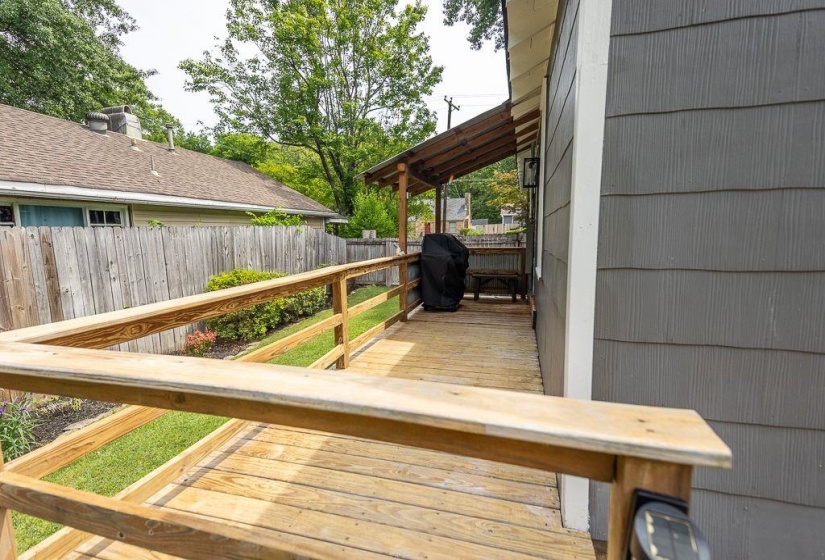 Expansive wood-finish deck with railing extending along the side of the property