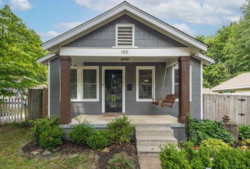 Gray siding exterior with white trim, featuring a covered front porch with two substantial columns