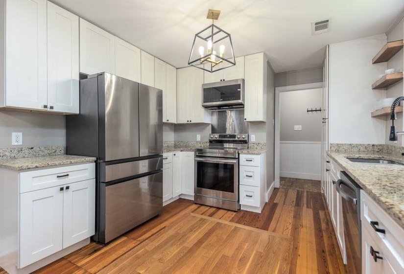 Well-appointed kitchen featuring a stainless steel French door refrigerator, matching range with microwave hood, and a built-in dishwasher