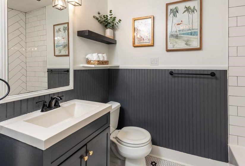 Bathroom featuring a dark wood-finish vanity with an integrated sink, matte black faucet, and a large framed mirror