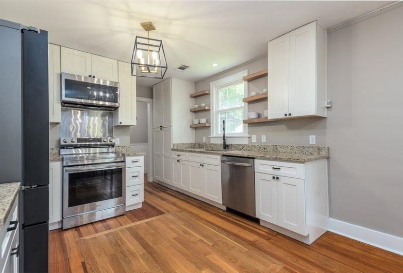 Kitchen featuring wood-finish flooring, white cabinetry, and granite countertops