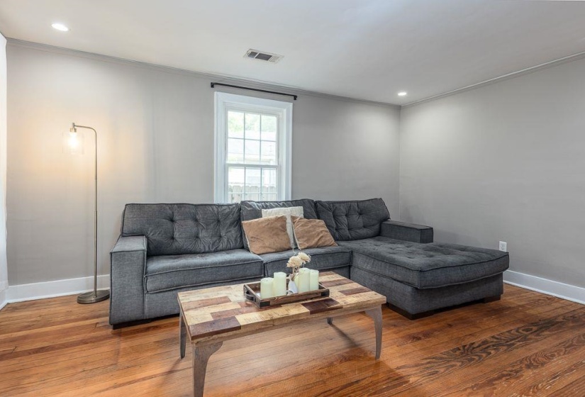 Interior room with hardwood flooring, neutral wall paint, white trim, and a double-hung window