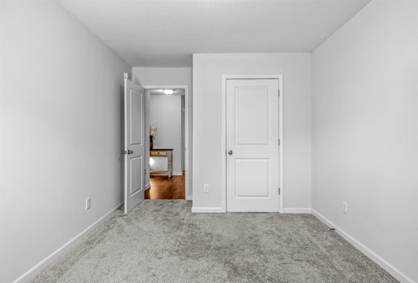 Light gray carpeted room featuring white walls, white paneled doors, and white baseboards