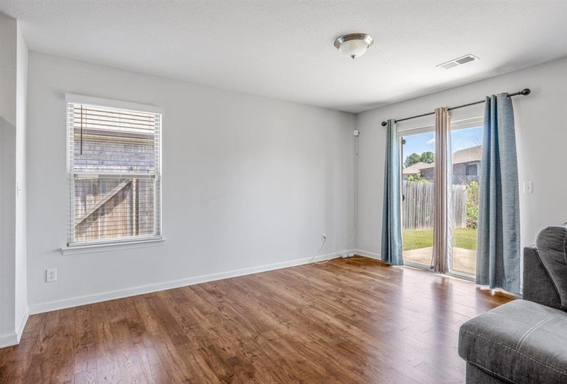 Spacious room featuring wood-finish flooring, light-colored walls, and a ceiling light fixture