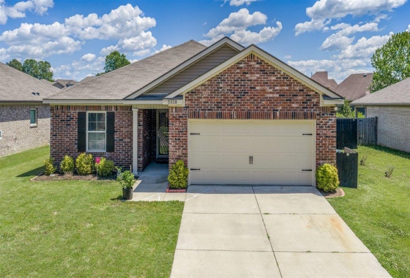 Brick facade with a neutral-toned garage door and concrete driveway