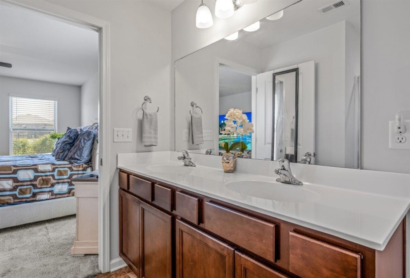 Bathroom vanity featuring a dual sink, white countertop, wood-finish cabinetry, and chrome fixtures