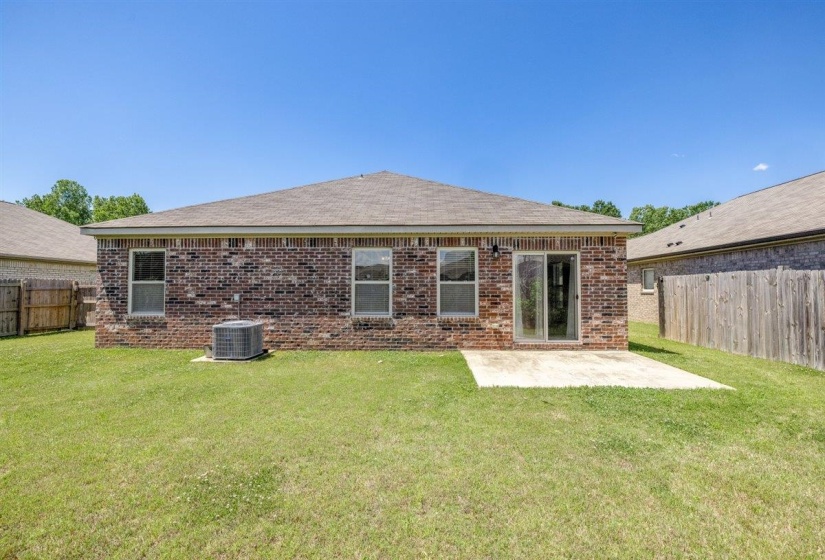 Brick exterior with a gabled roofline, featuring multiple windows, a sliding glass door, and an exterior concrete patio