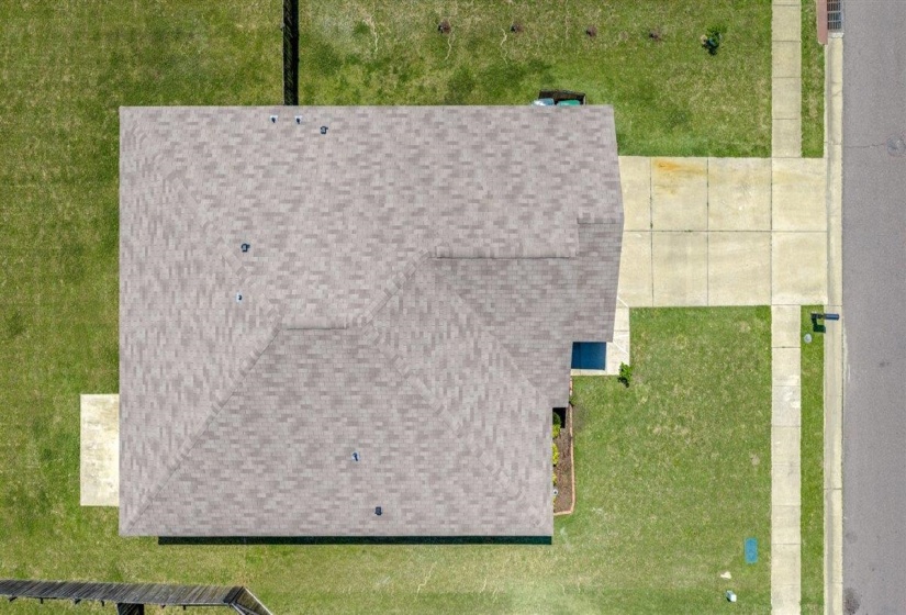 Gabled roofline with asphalt shingles, concrete driveway, concrete pathway, surrounding lawn