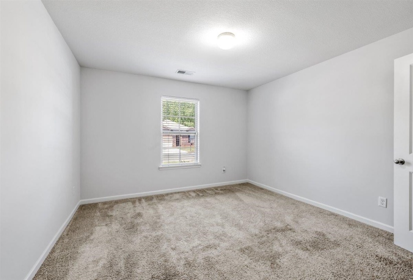 Carpeted room featuring a single window with blinds, white walls, and a ceiling-mounted light fixture