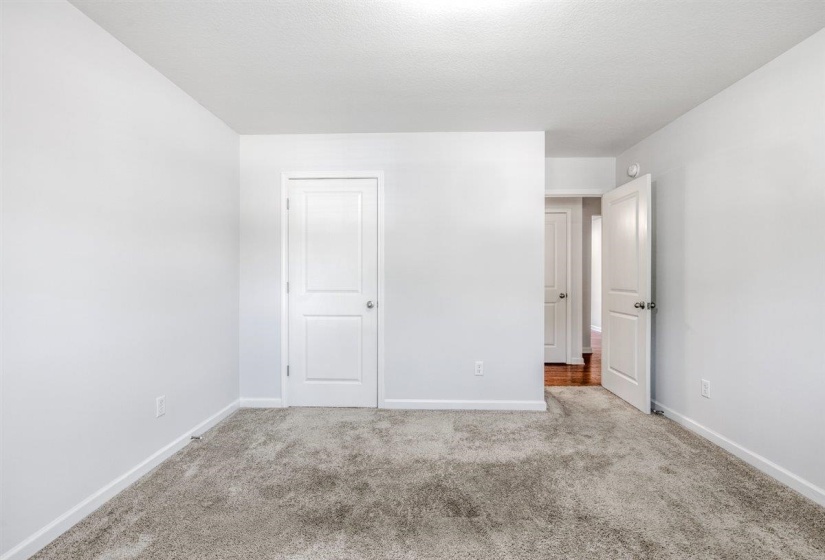Spacious room featuring light gray carpeting, neutral wall finishes, white baseboards, and two-panel interior doors