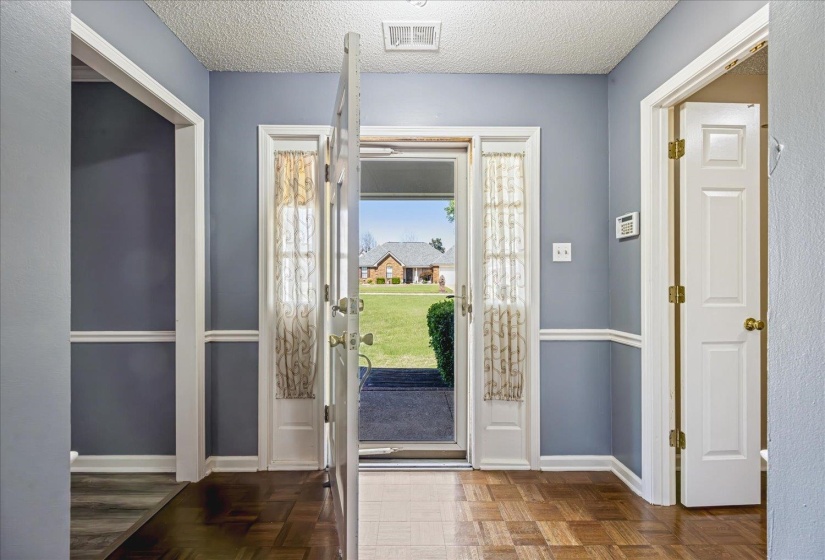 Entryway featuring wood-finish flooring, light blue walls with white wainscoting, and an open door with sidelight windows