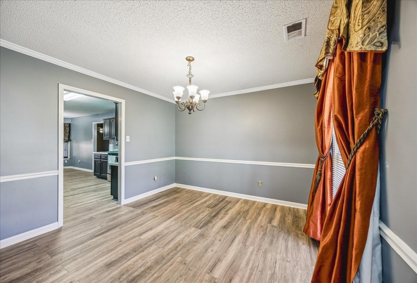 Dining area featuring wood-finish flooring, two-tone wall paint, crown molding, and a chandelier light fixture