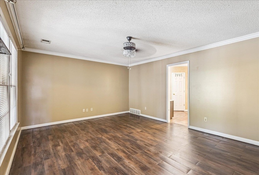 Spacious room featuring wood-finish flooring, neutral wall tones, and white crown molding