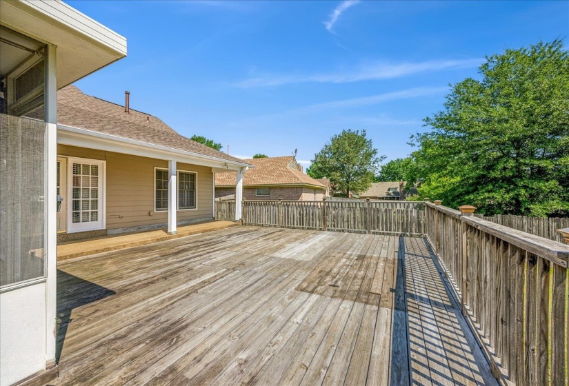 Expansive wooden deck with full railing and a covered patio area