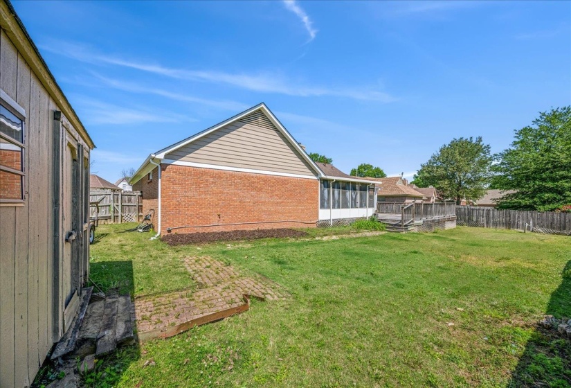 Expansive grassy yard area featuring a brick and siding exterior, a screened porch, and an elevated wooden deck