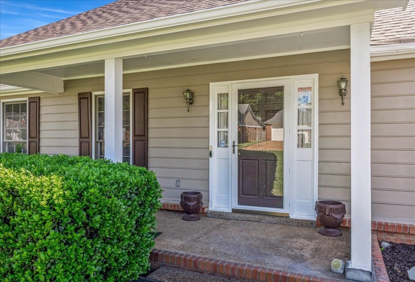Inviting front entry featuring a storm door, sidelight windows, and twin wall-mounted carriage lights