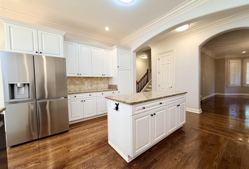 Bright kitchen featuring white cabinetry, granite countertops, a diamond-patterned backsplash, and wood-finish flooring