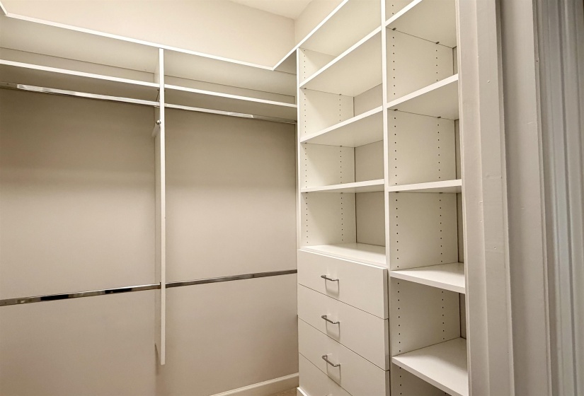 Double custom closet system featuring white shelving, multiple hanging rods, and built-in drawers with modern pulls