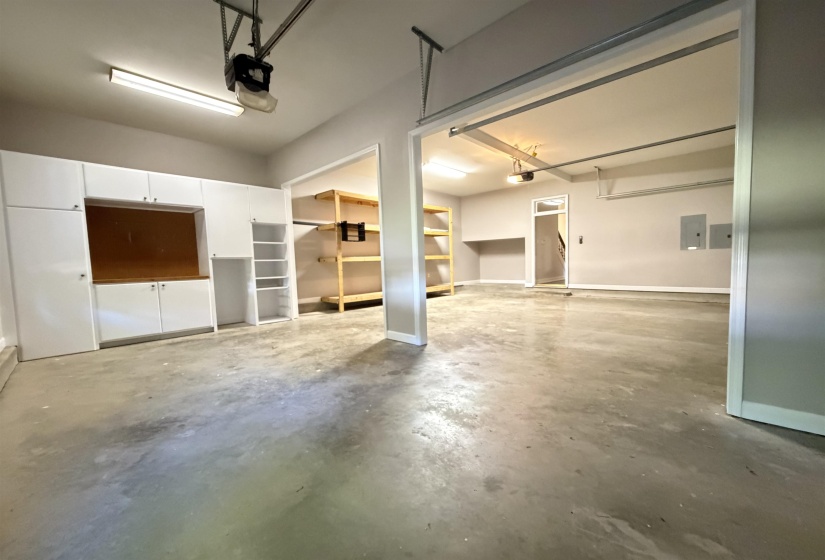 Garage with built-in white cabinetry, integrated workbench area, and additional wood shelving
