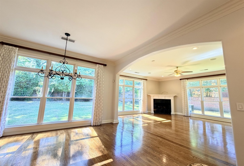 Hardwood flooring spanning two expansive rooms, featuring an arched doorway and large windows