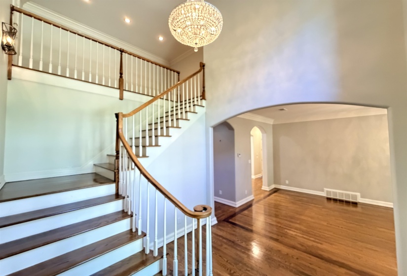 Two-story foyer featuring a grand staircase with dark wood-finish treads and white risers, complemented by a wood-finish handrail and white balusters
