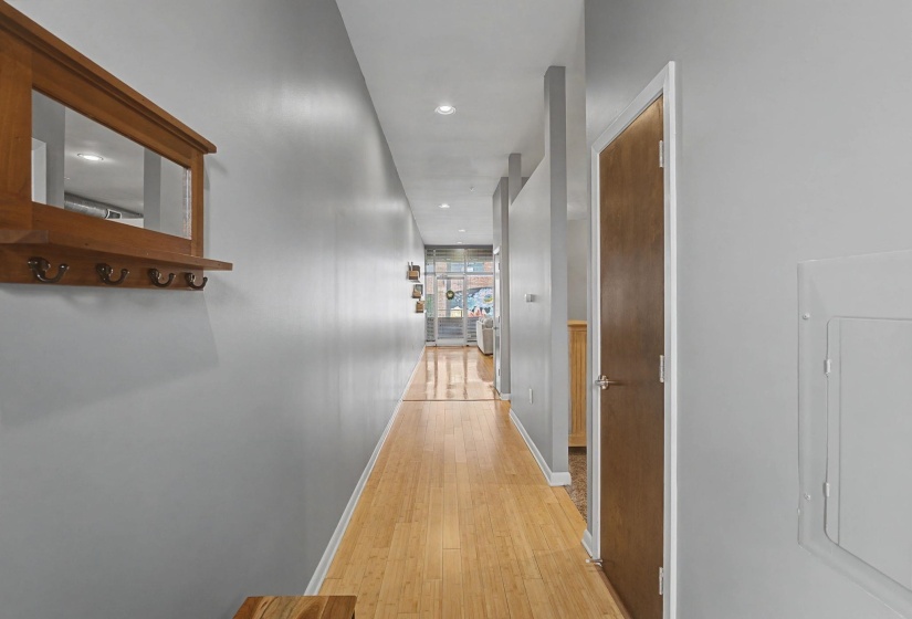 Corridor with light wood finished floors, electric panel, and recessed lighting