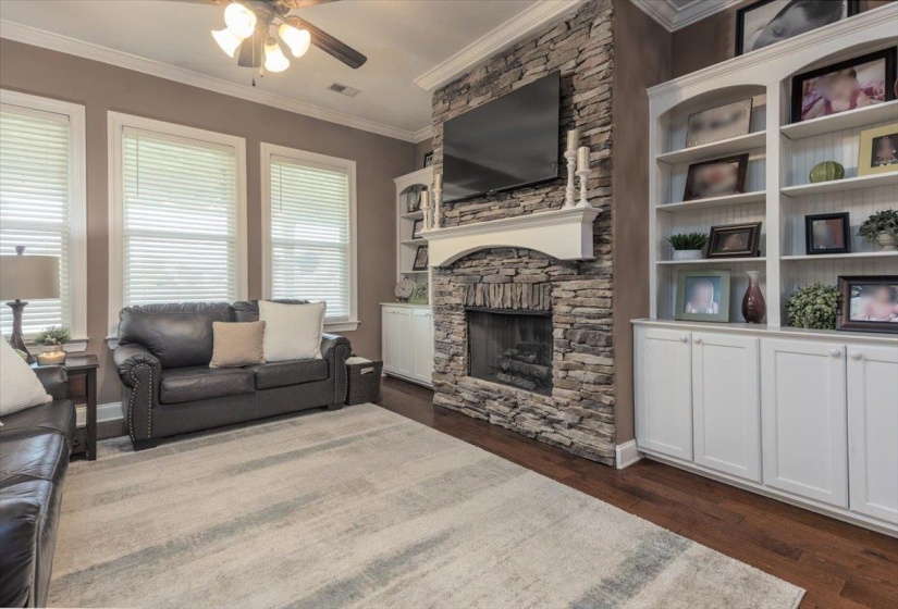 Stone fireplace with a white mantel and hearth, flanked by custom built-in shelving and lower cabinetry