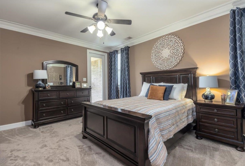 Neutral-toned room featuring crown molding, a ceiling fan with integrated lighting, and a glass-paned door