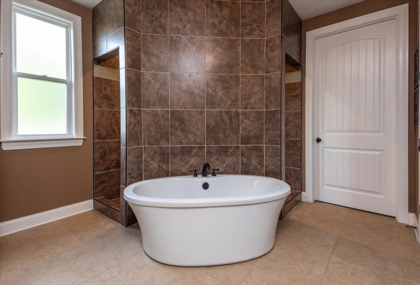 Freestanding soaking tub with dark-toned fixtures
