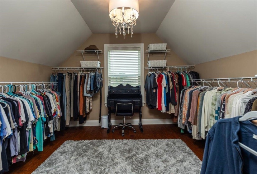Attic space featuring wood-finish flooring, sloped ceilings, and built-in closet organization systems