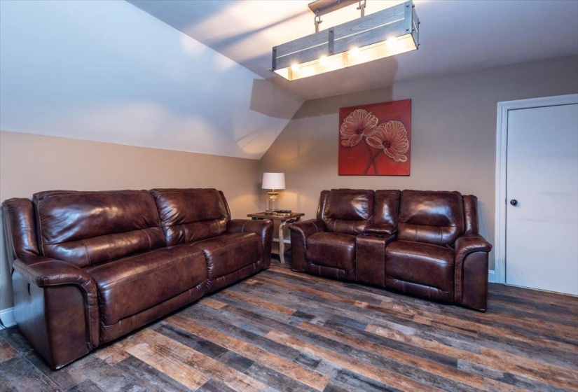 Room featuring wood-finish flooring, a neutral wall color, and a vaulted ceiling