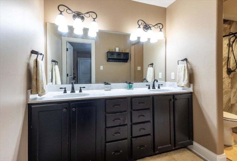 Dual vanity featuring dark wood cabinetry, white countertop, individual sinks, and decorative light fixtures