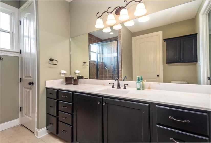 Double vanity featuring a light-toned countertop, dark cabinetry, and dual undermount sinks
