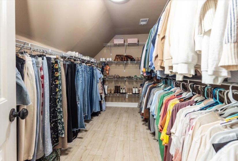 Spacious walk-in closet featuring wood-finish flooring and sloped ceiling