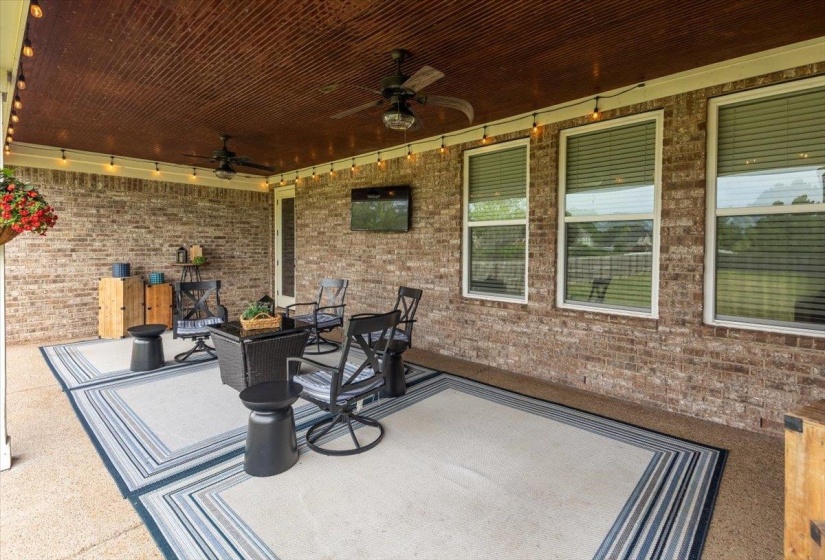 Covered outdoor patio featuring a brick exterior wall, a wood-paneled ceiling, and recessed lighting