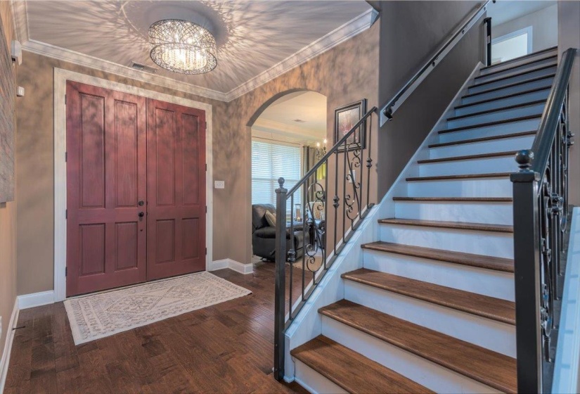 Grand entryway featuring a dual-panel front door, wood-finish flooring, and a decorative chandelier