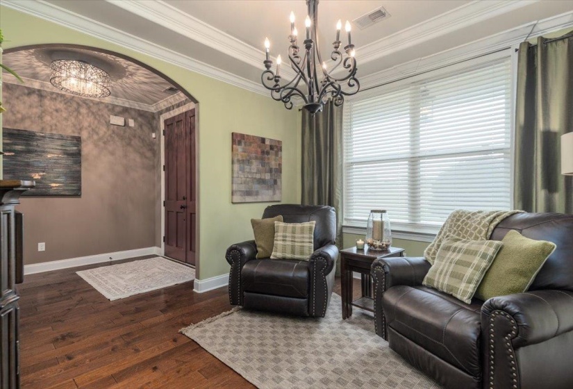 Warm wood-finish flooring, an arched entryway, and crown molding define this welcoming interior