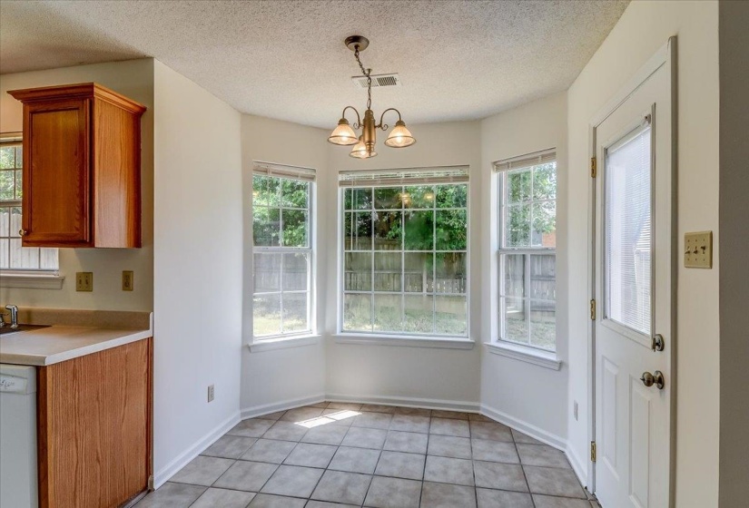 Breakfast nook featuring a bay window, tiled flooring, and a multi-light fixture