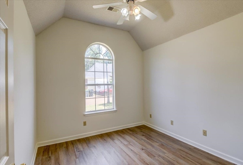 Vaulted ceiling room featuring an arched window