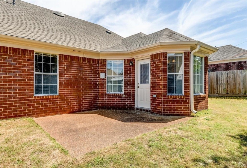 Rear exterior featuring a brick facade, multiple windows, and a patio area