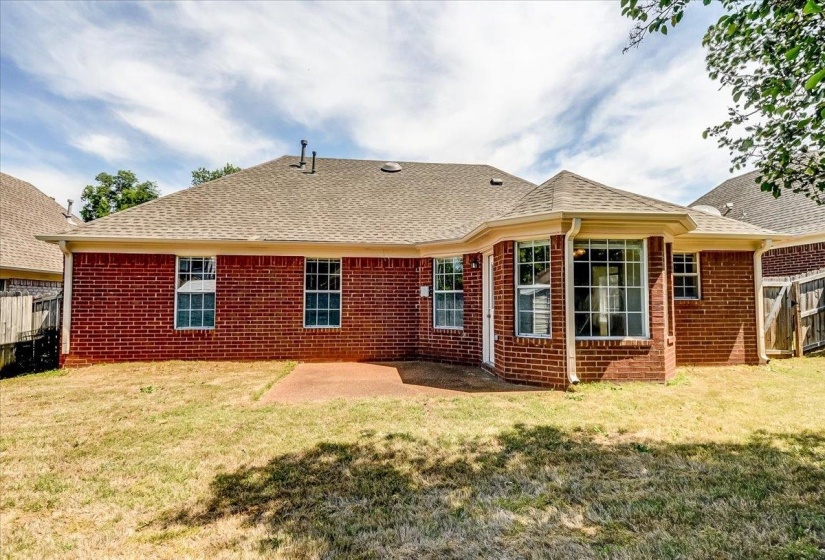 Brick exterior with a gabled roofline, featuring multiple windows, and a rear patio space