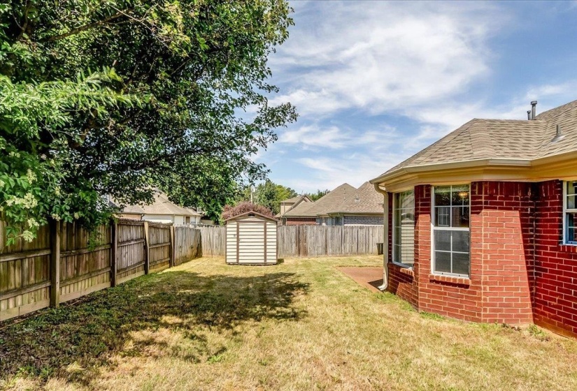 Fenced backyard featuring a storage shed