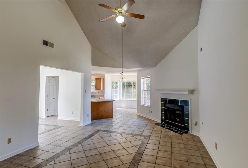 Spacious living area featuring a vaulted ceiling and a ceiling fan with integrated lighting