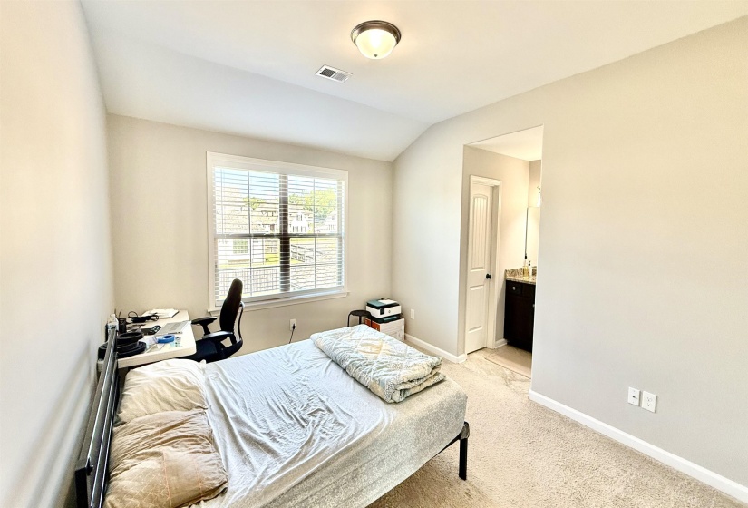 Bedroom featuring light colored carpet, ensuite bath, and vaulted ceiling