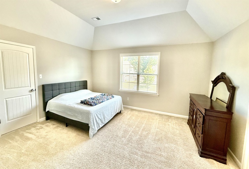 Bedroom featuring light colored carpet and vaulted ceiling