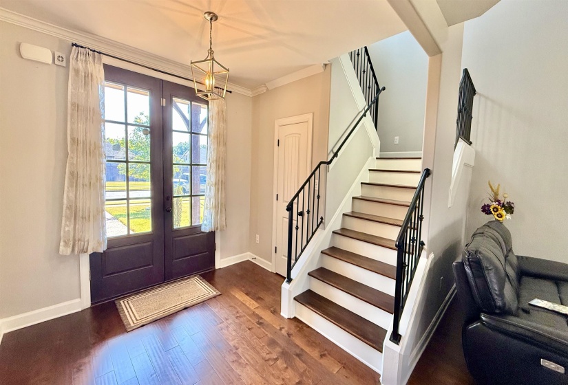 Foyer entrance featuring stairs, french doors, crown molding, and wood finished floors